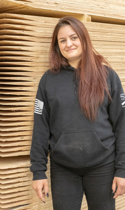 A young female employee works in the manufacturing facility of a mass timber fabricator